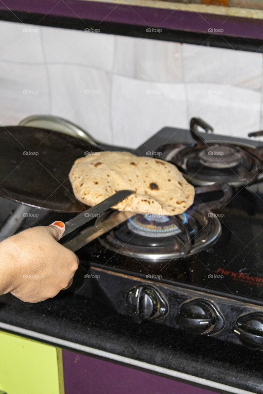 Handling a roti with tong to make it finally ready to eat