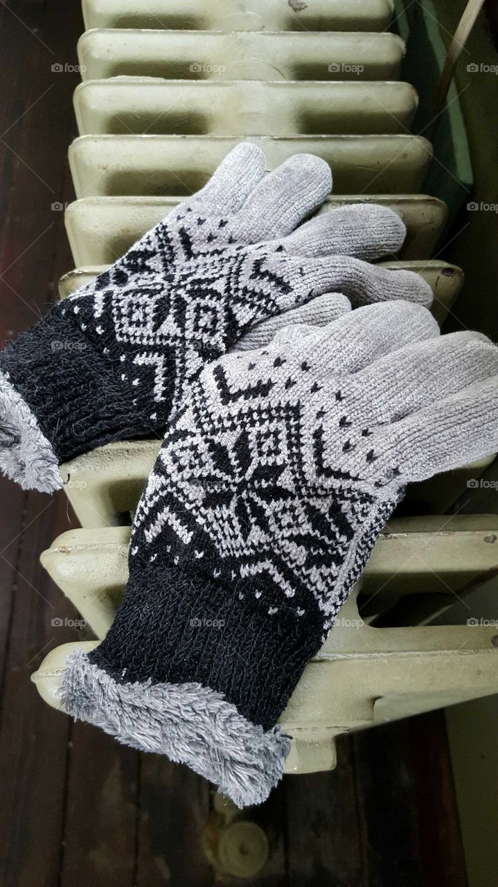 Winter gloves drying out on a cast iron radiator after getting wet in the snow.