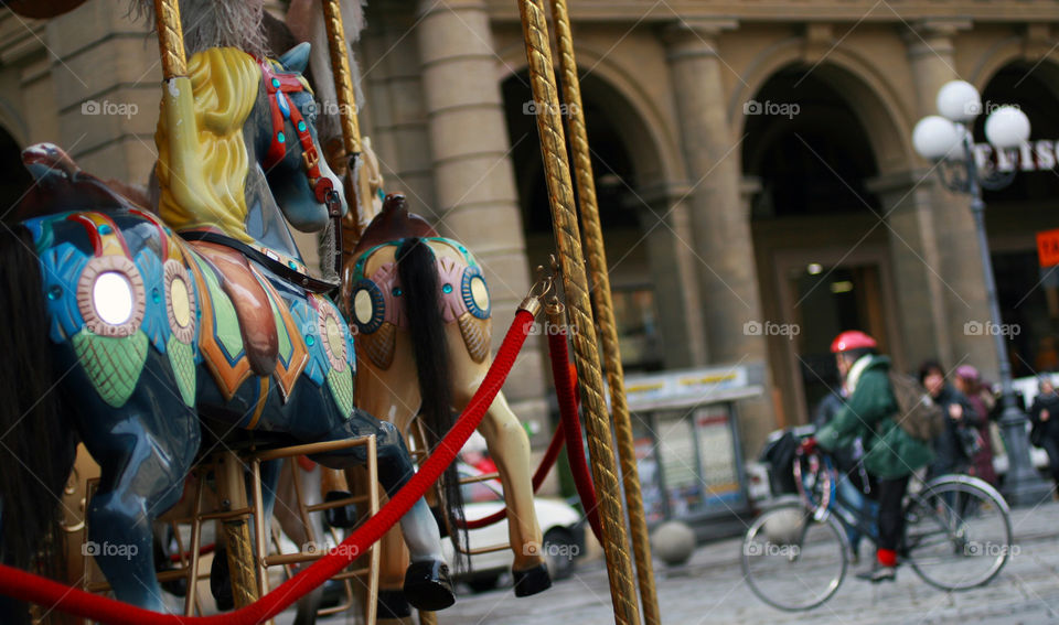 Woman in a bike and part of a carrousel 