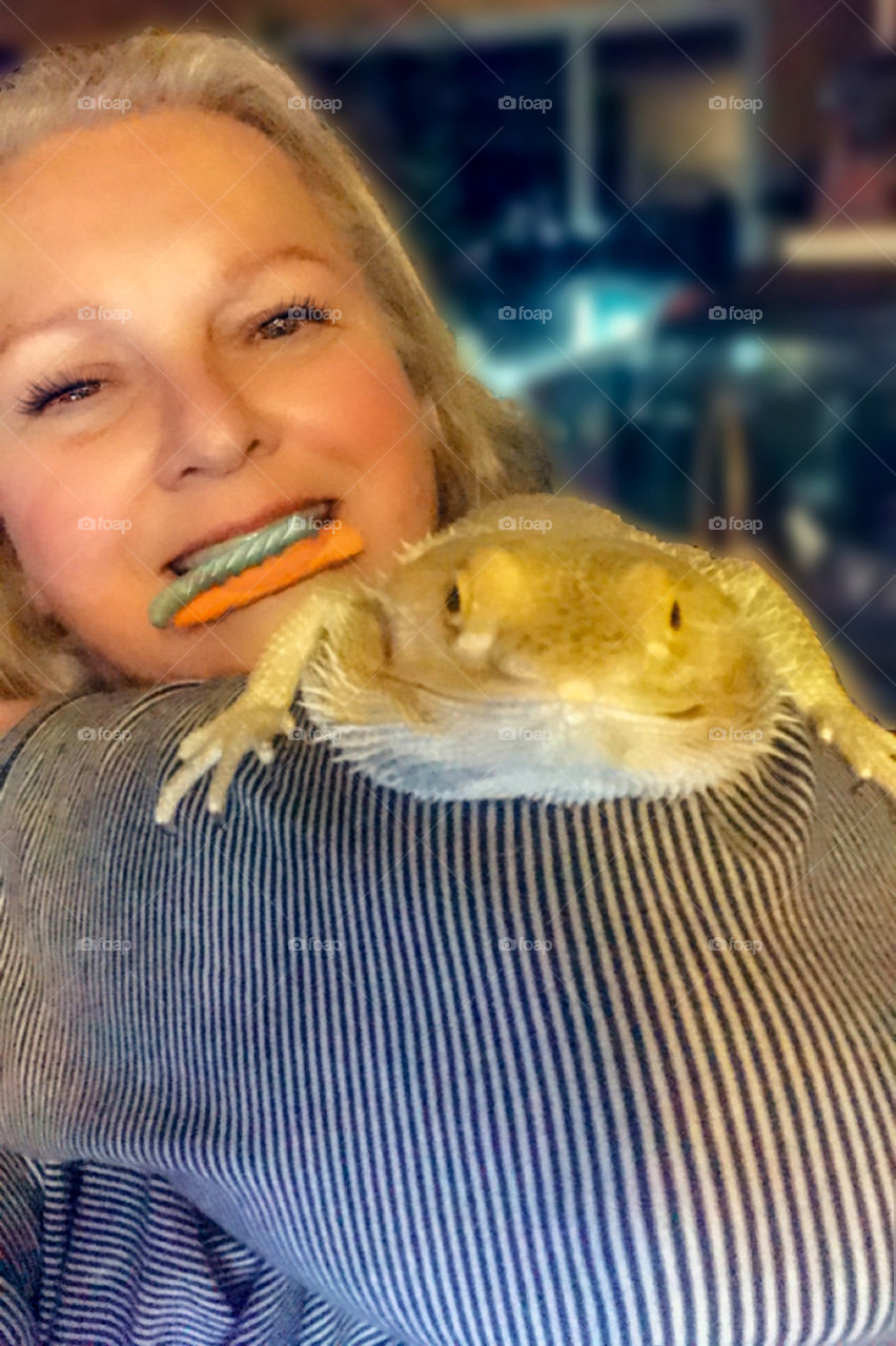 Selfie with my bearded dragon. This is tricky because he generally likes to move around & get as high up on me as possible. I was trying to bribe him with a turquoise hornworm on a piece of carrot. He was more interested in the dragon on the phone! 🐉