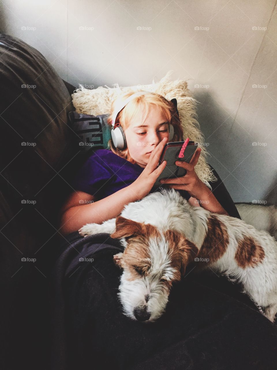 Girl using her phone with a dog in her lap