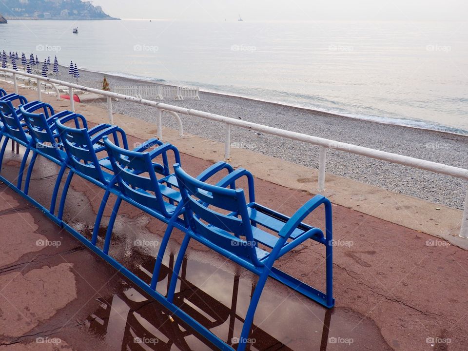 Iconic blue chairs on the Promenade des Anglais overlooking the sea.
