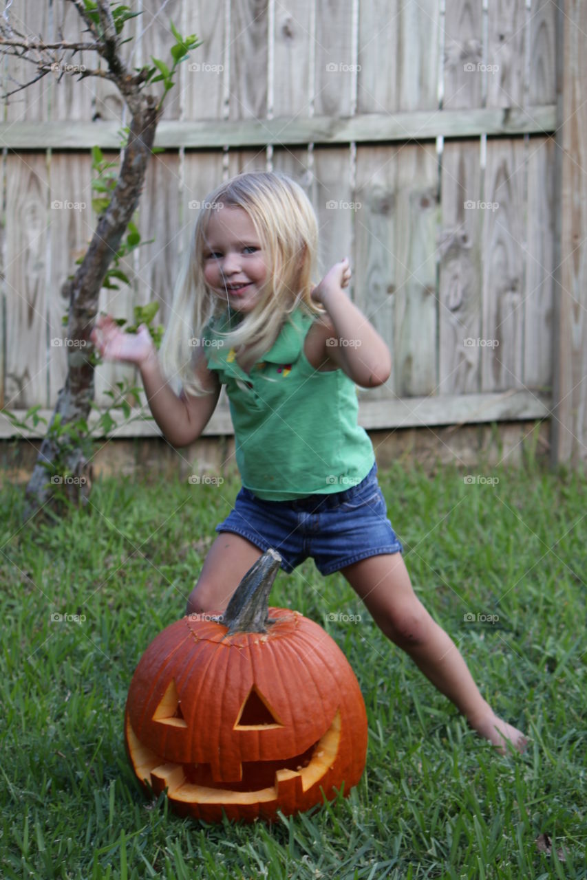 Girl playing in grass with pumpkin