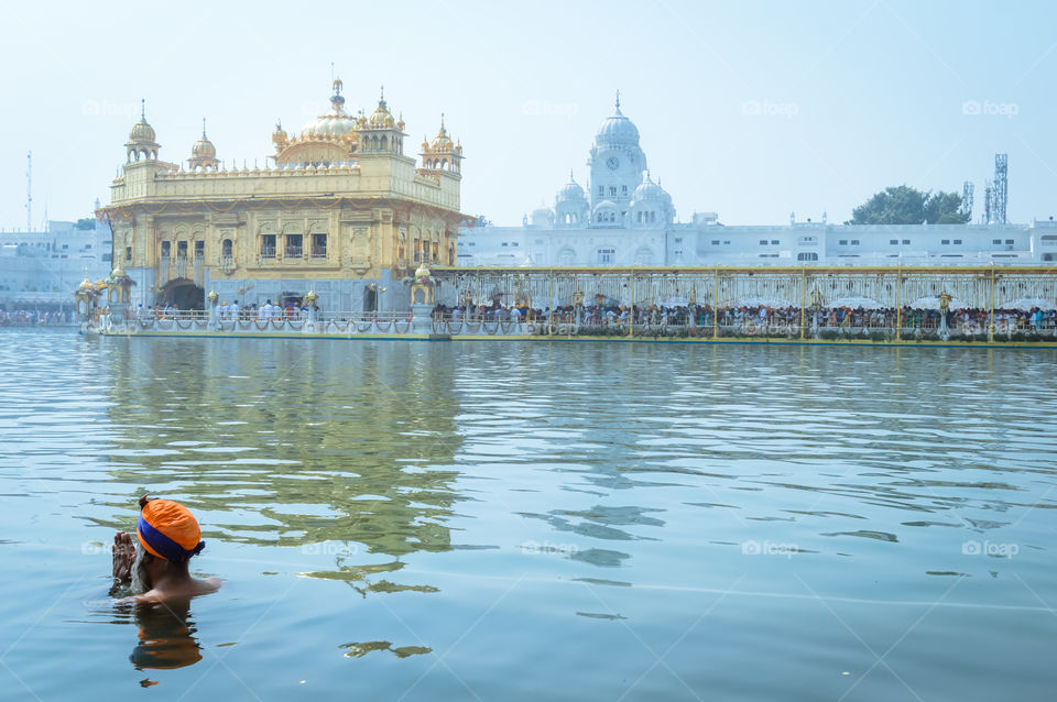 Unidentifiable Punjabi Sikh pilgrim devotee "Nihang Warrior" taking bath and prayer in pond and meditating in front of Golden Temple ("Harmandir Sahib Darbar Gurudwara") Amritsar, Punjab, India, Asia.