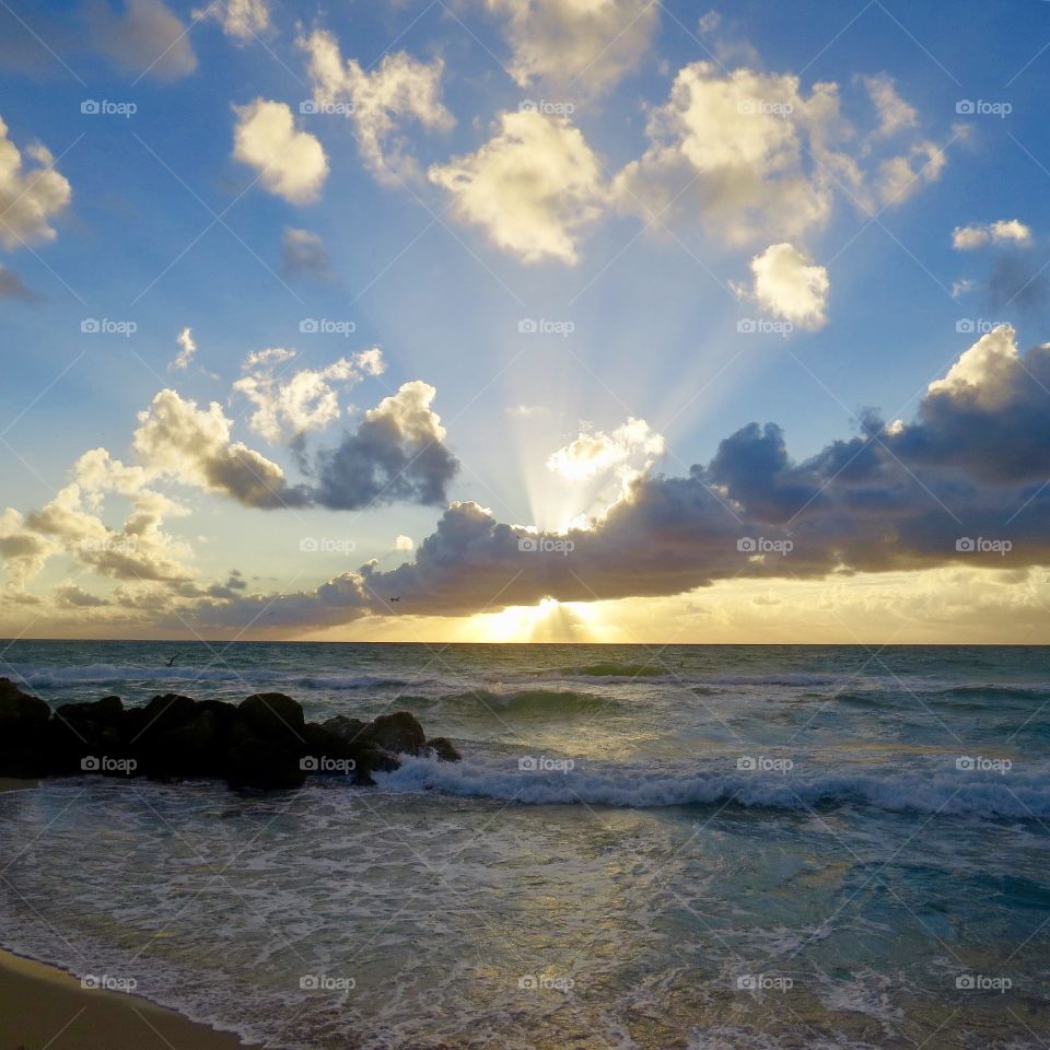 Sunlight bursts behind clouds on shores of Atlantic Ocean 