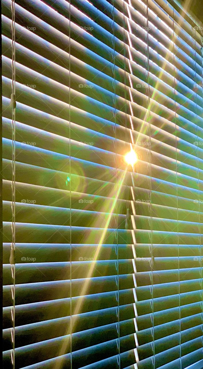 sunlight through closed window blinds in the morning