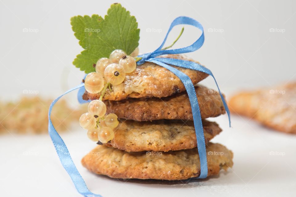 homemade oatmeal cookies tied with a ribbon and garnished with a sprig of white currant