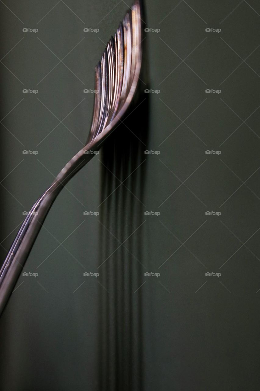 Close up of silver forks standing on green wall 