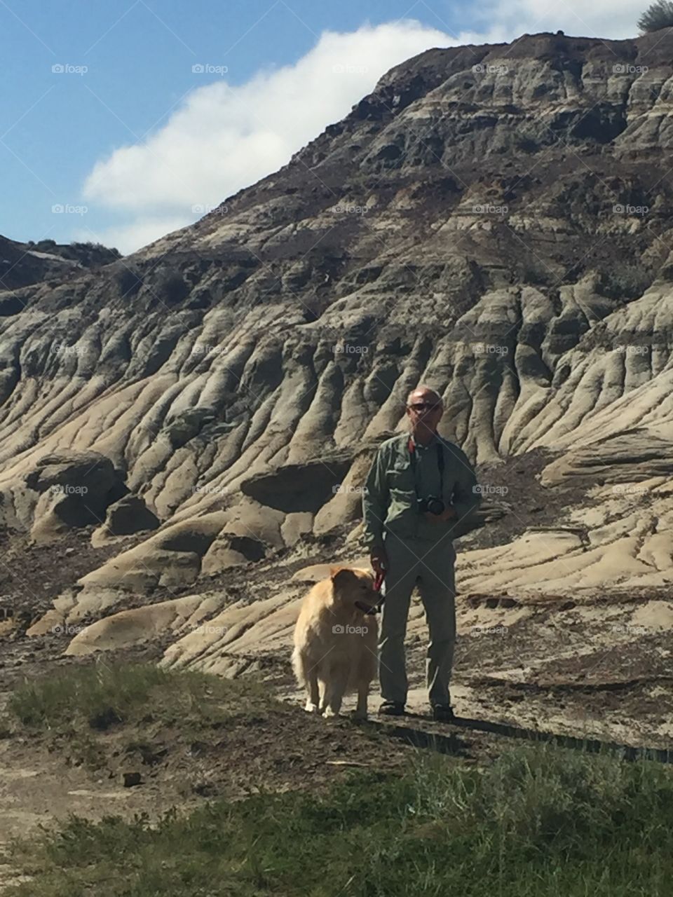 Senior man standing in front of mountain with dog