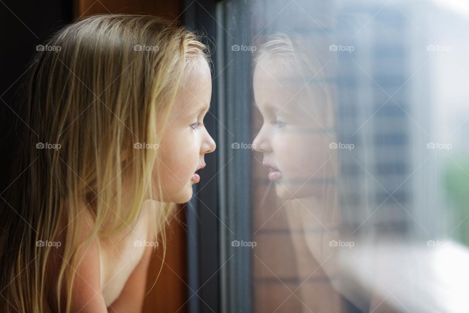 Little girl looking through the window 