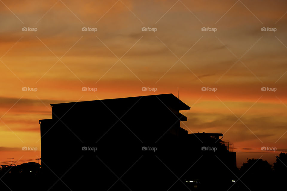 Beautiful light of Sunset with clouds in the sky reflection behind the building.