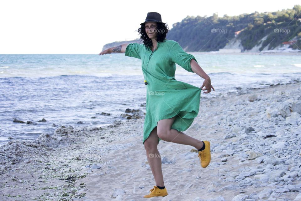 A woman in green summer dress on the beach