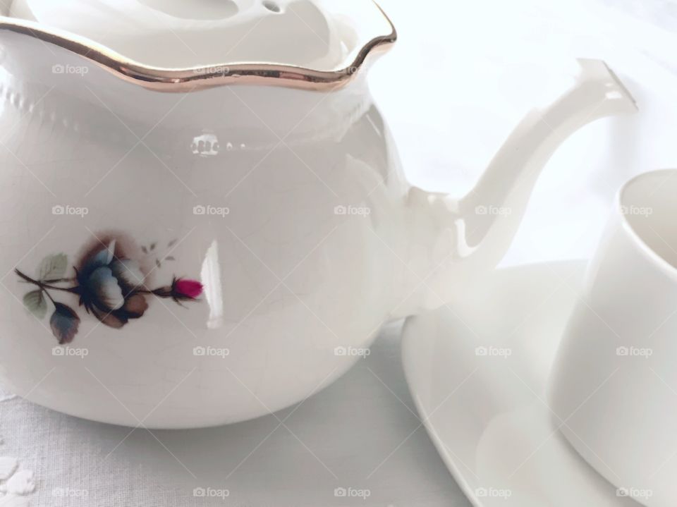 Tea Time - white porcelain teapot with painted burgundy and white wild roses, white teacup, on white tablecloth