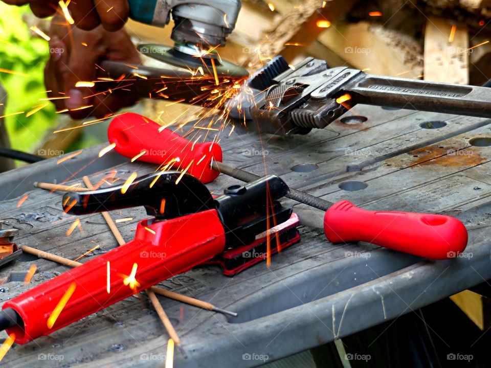 Color Red:  Sparks flying as a man works on a welding project using red handled tools