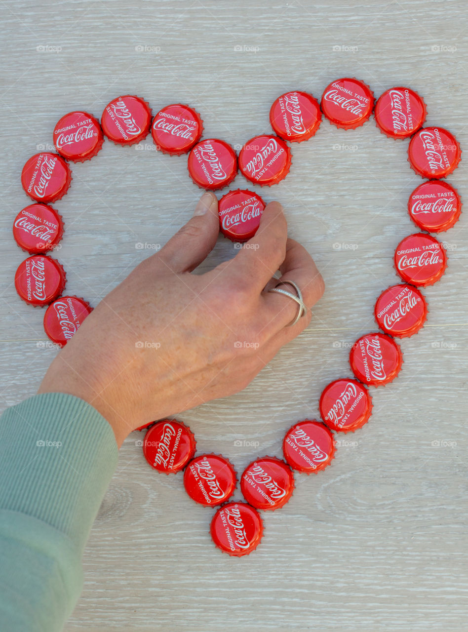 hand and Coca Cola bottle caps