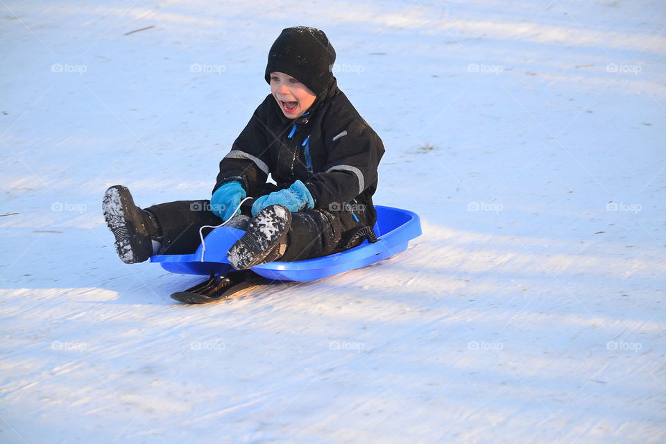 Boy sledding down the hill laughing