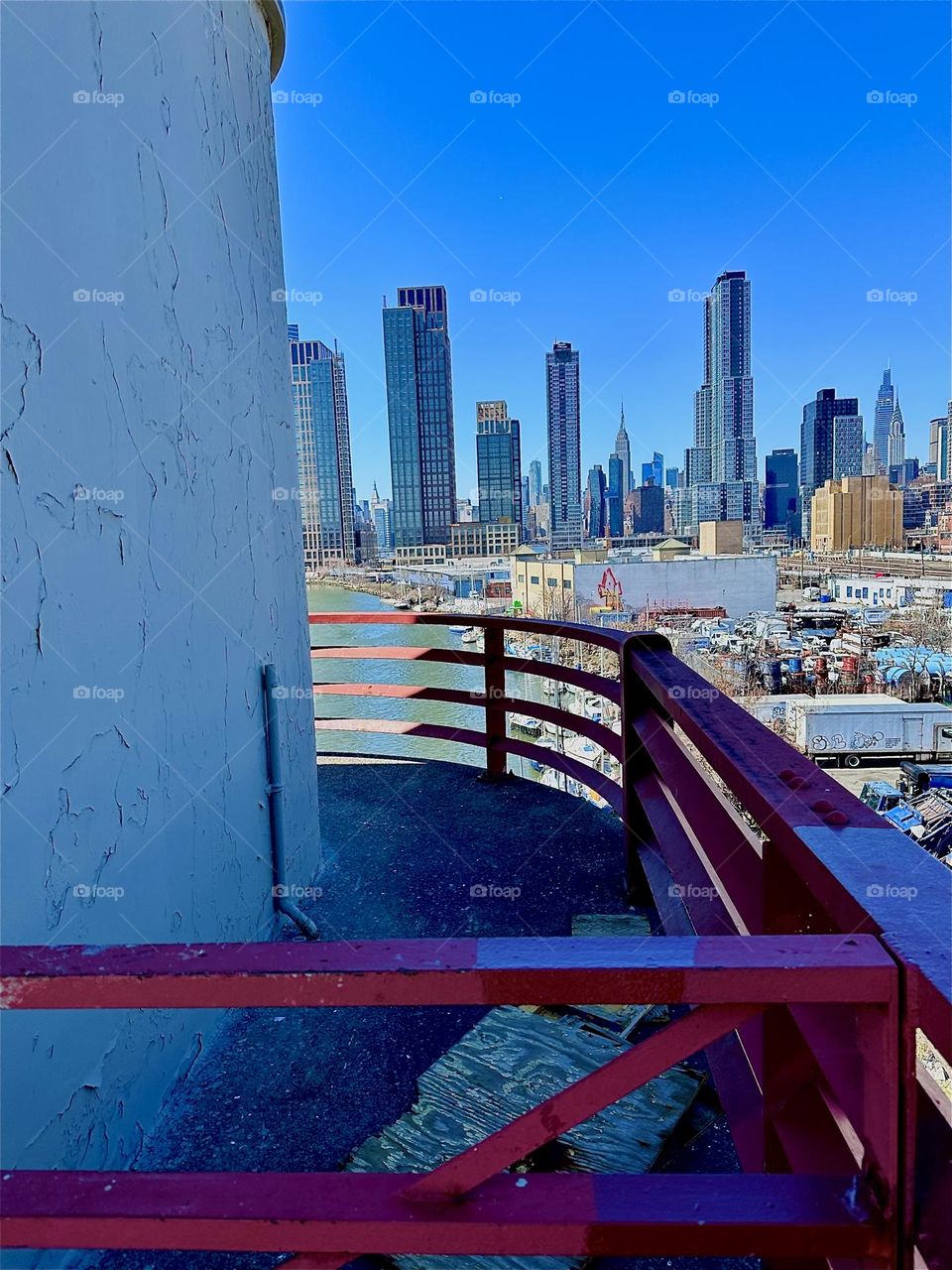This is the central outpost of the “Pulaski Bridge” at “Newtown Creek” that connects LIC, Queens to “Greenpoint”, Brooklyn. In the far distance behind LIC we see the “Manhattan” skyline incl. the “Empire State Bldg”. 2024. Hypnotic Productions