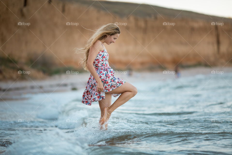 Portrait of beautiful young woman near the sea at sunset