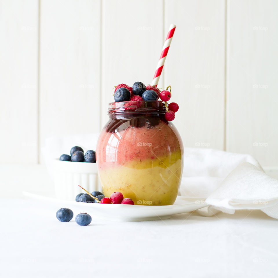 Colorful smoothie with banana, strawberry, raspberry and blueberry in jar
