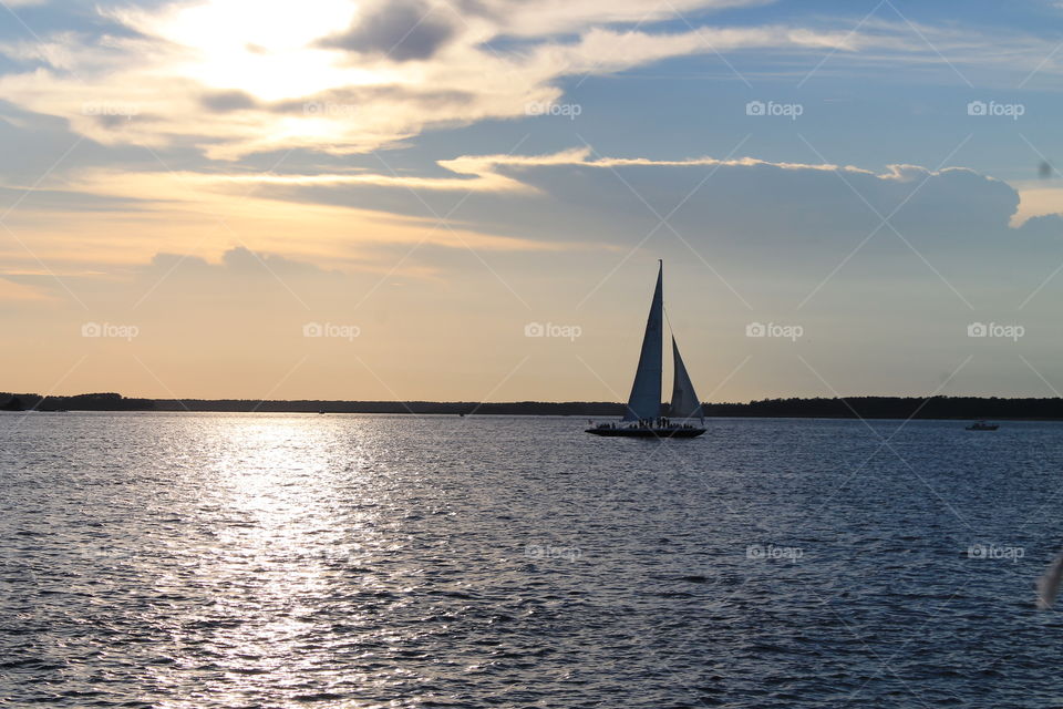 Beautiful scene of a sailboat sailing in the ocean at sunset.