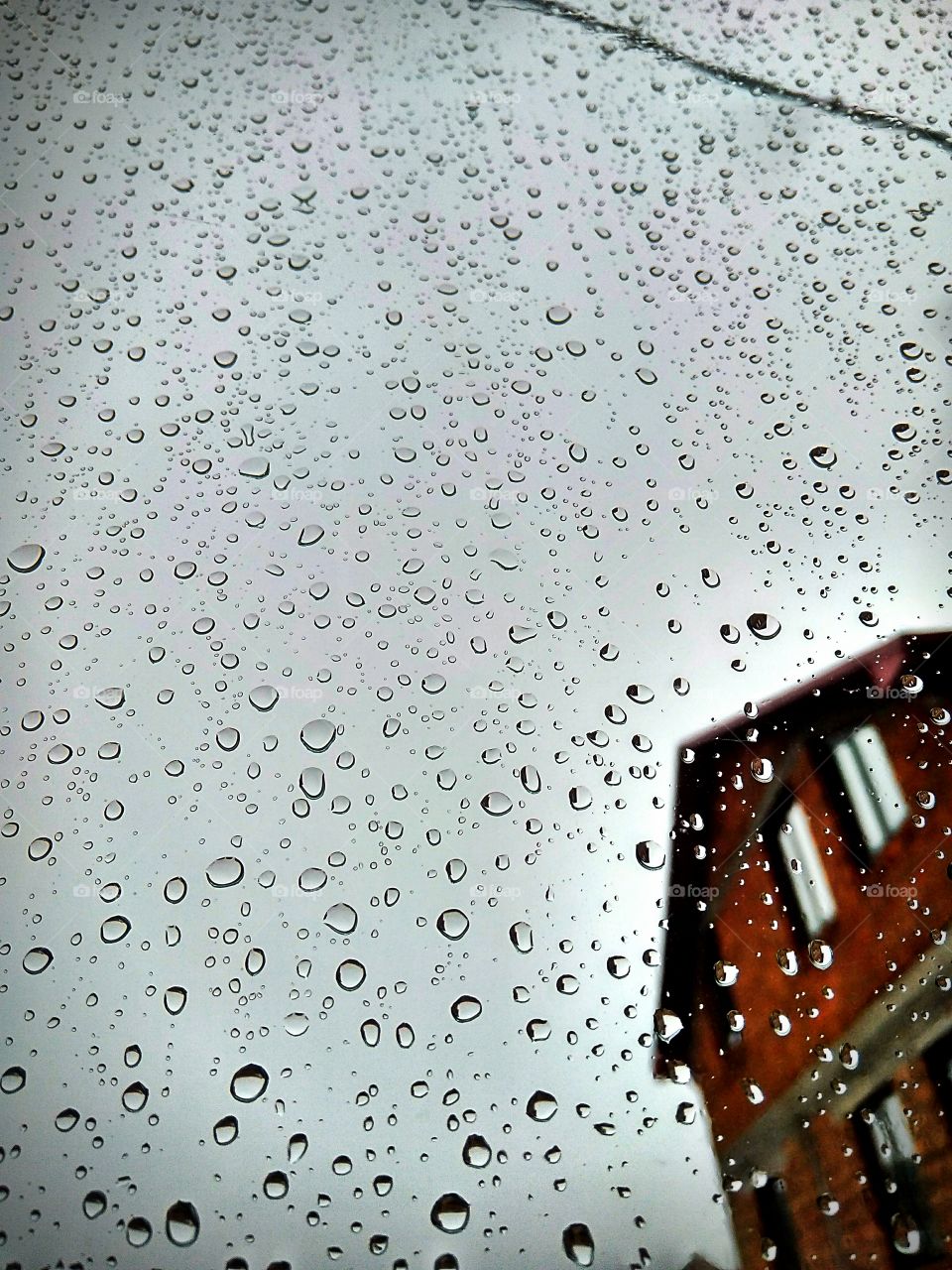 from the window you can see the rain on the glass and the house