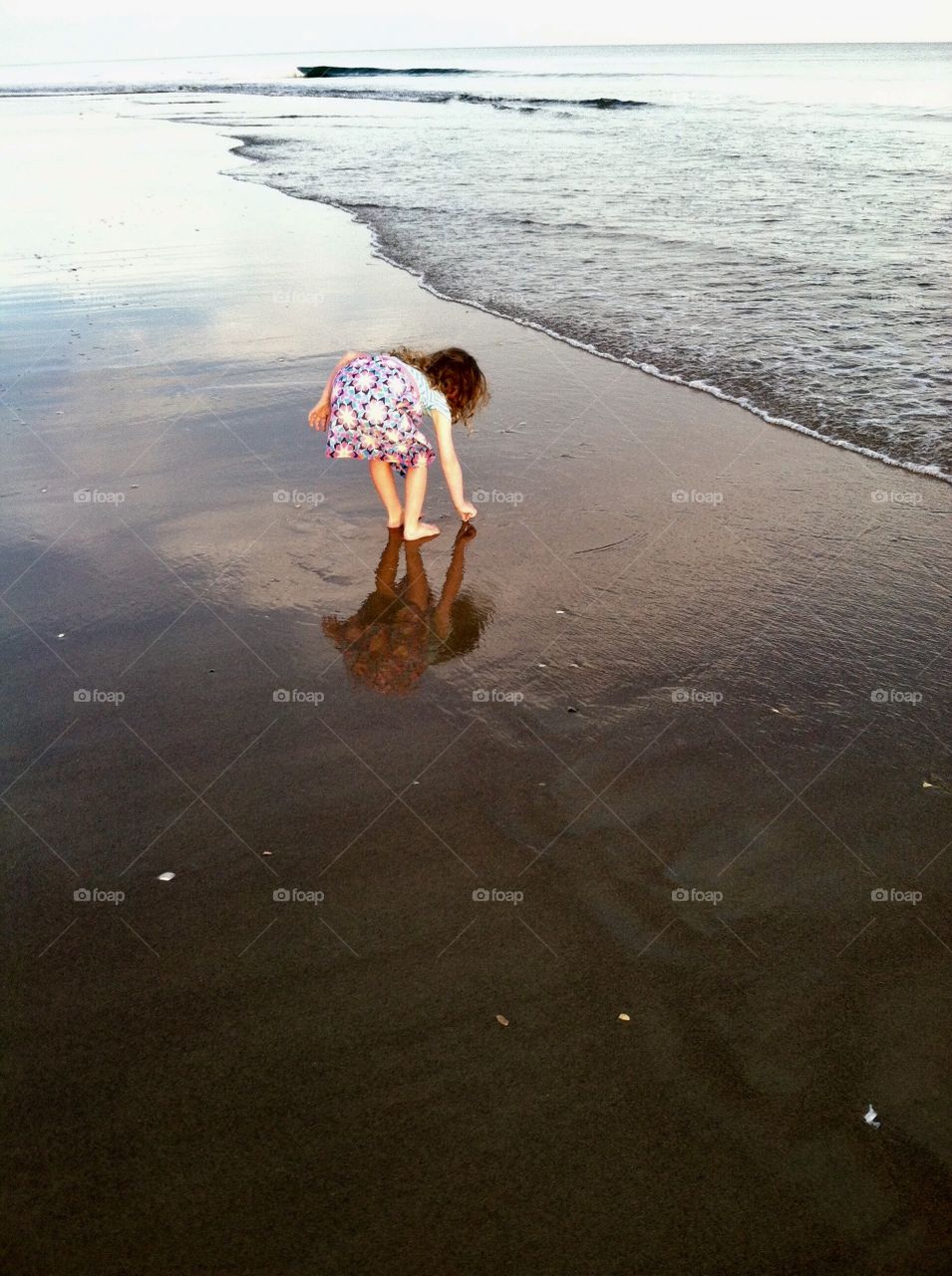 Little girl finding seashell treasures on the beach of Emerald Isle North Carolina