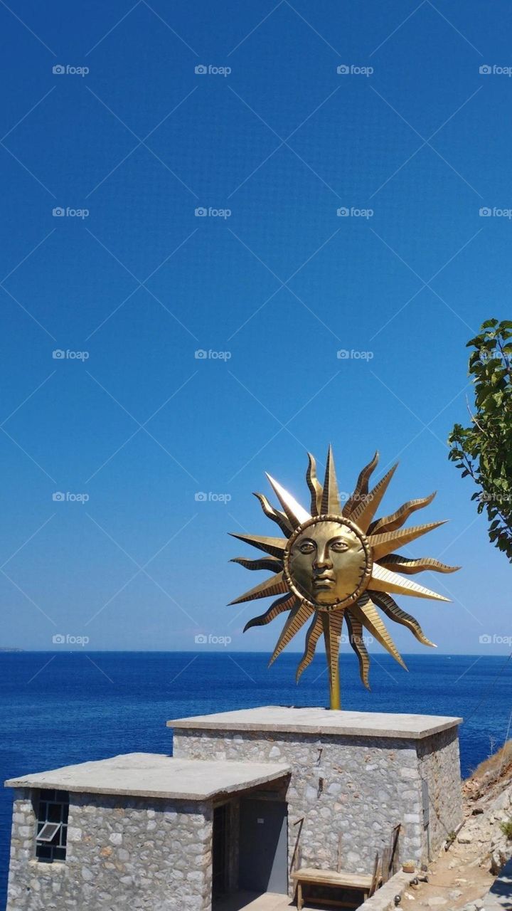 Above a Slaughterhouse in Hydra is Apollo Wind Spinner, a 30 foot wide reflective wind spinner that greets people entering the port on one side and, on the other, welcomes people walking to the building. The face of the sculpture is that of Apollo.