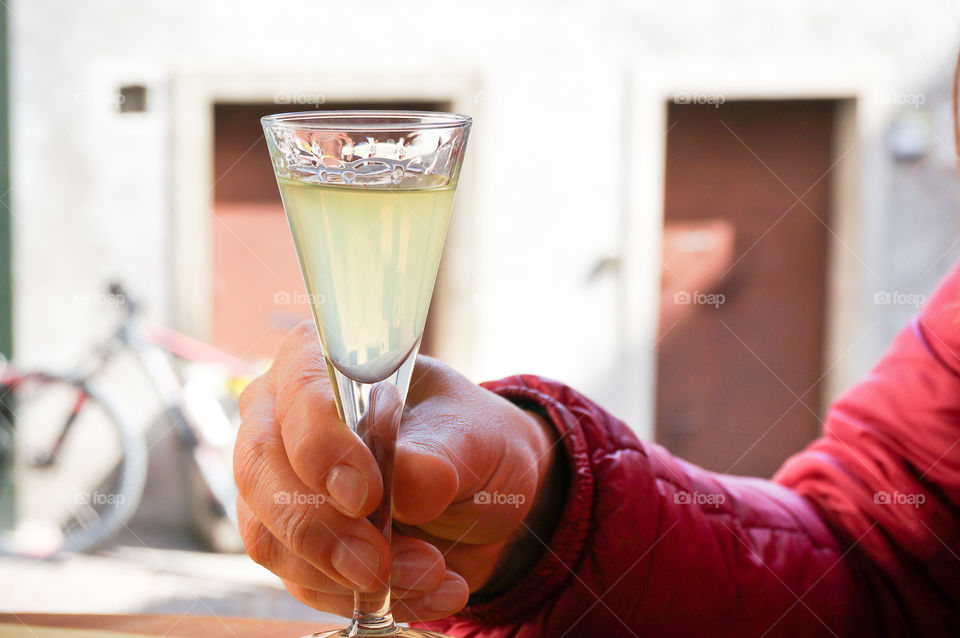 Limoncello lemon liqueur traditional Italian drink in hands of a woman