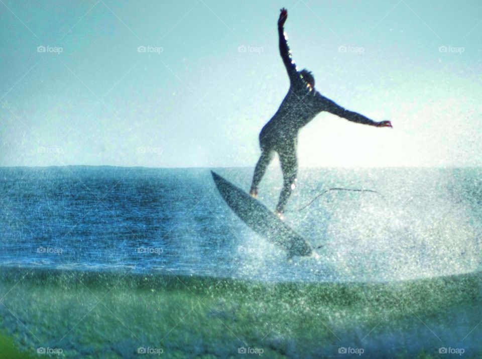 Surfer jumping his board over a wave at Año Nuevo beach in Northern California