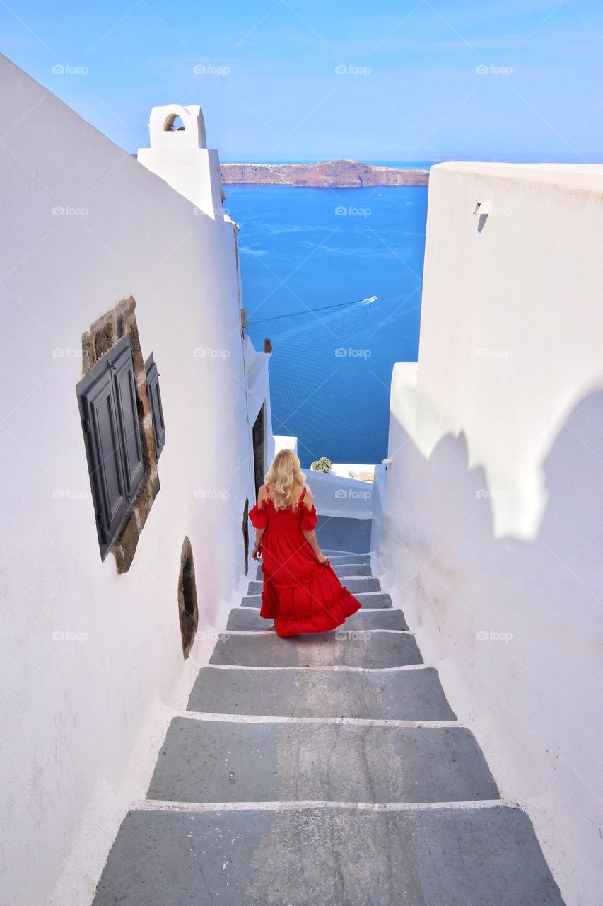 blonde woman going down stairs in red dress in santorini