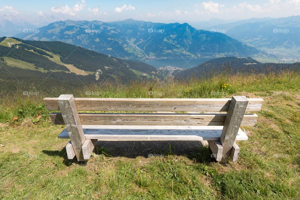 Wooden bench on the top of the mountain in the Austrian alps with panoramic view over the lake and the valley 