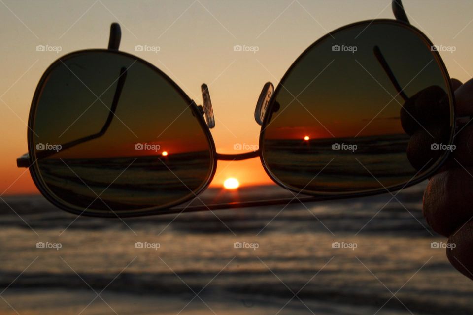 Sunglasses pointing at the setting sun with sun set looking like a face.