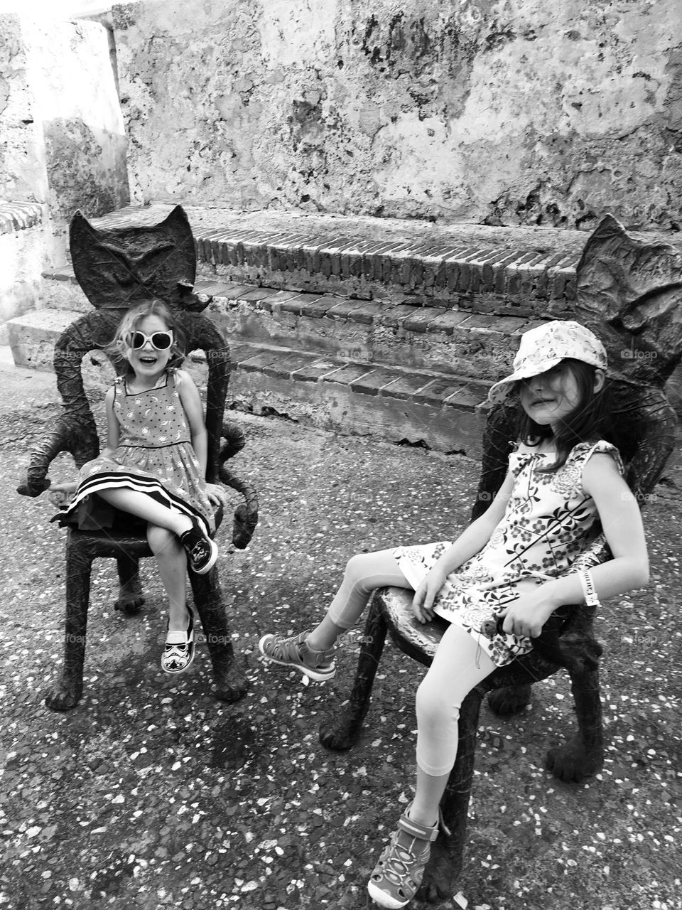 Two young girl travelers relaxing on artistic cat chairs in Puerto Rico. 