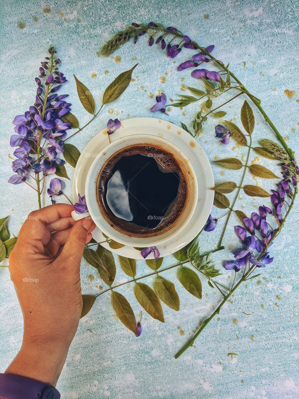 Background of a cup of hot coffee on the table with beautiful flowers close-up. Top view.