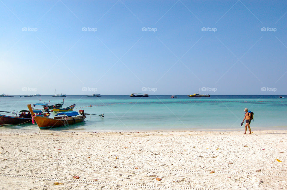 Tourists walk on the sands at the white background Sea and fishing boats at Koh Lipe  ,Satun in Thailand. March 11, 2014.