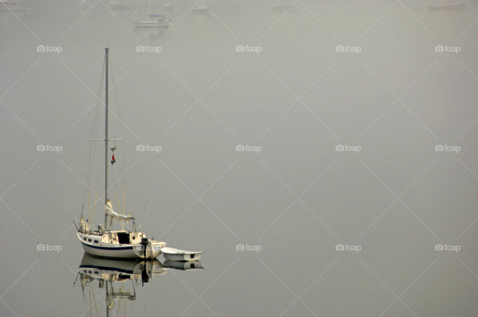 Sailboat and dinghy reflecting in the calm waters of the bay