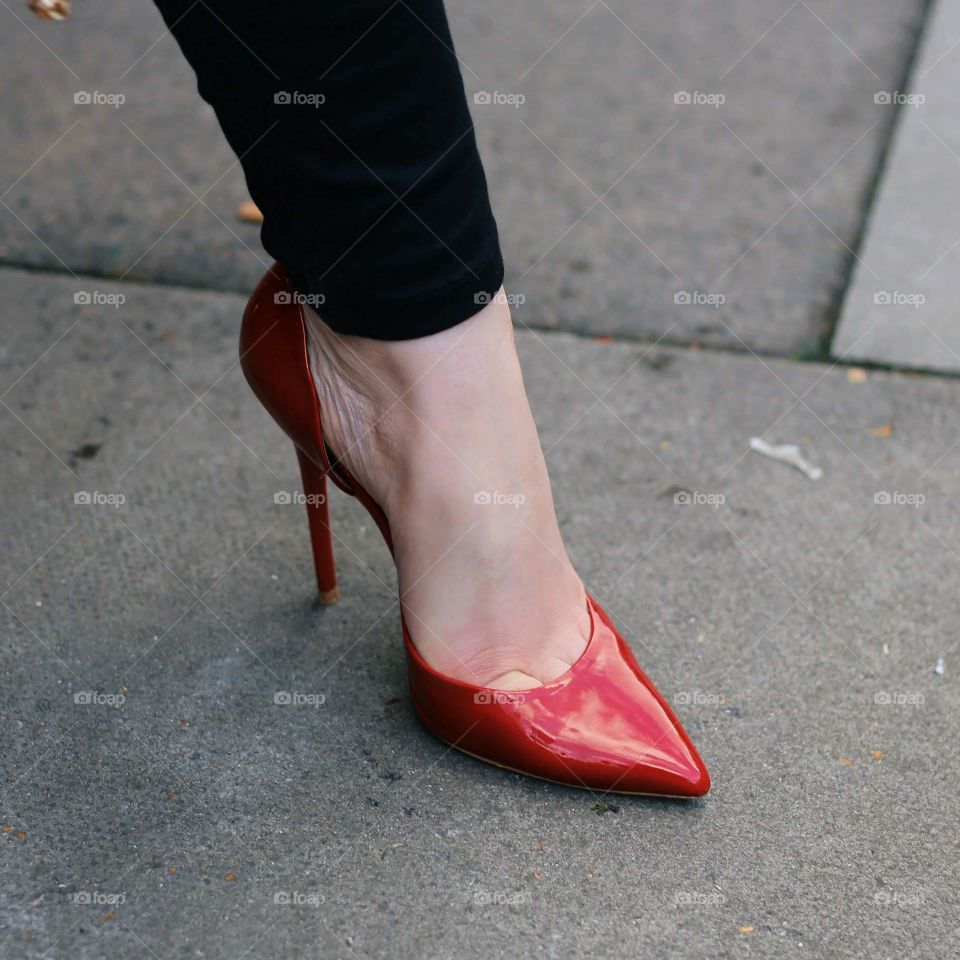 woman's foot wearing red high heels and black skinny trousers standing in a power pose