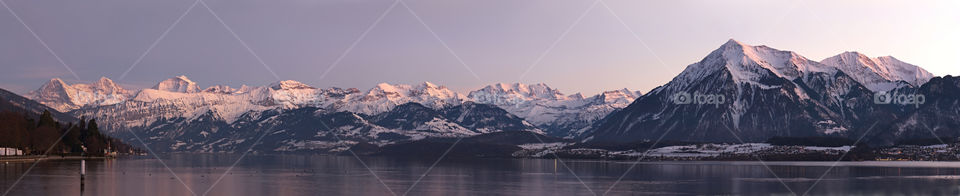 Panorama of Alpine snow mountains behind lake thun.