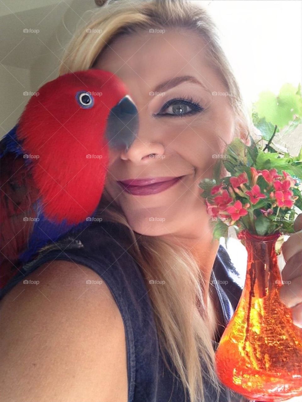 Lighthearted moment between a woman and her red parrot.