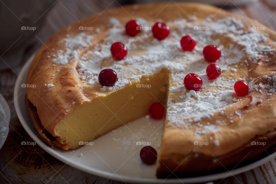 Cheesecake with cranberries and sugar on wooden background