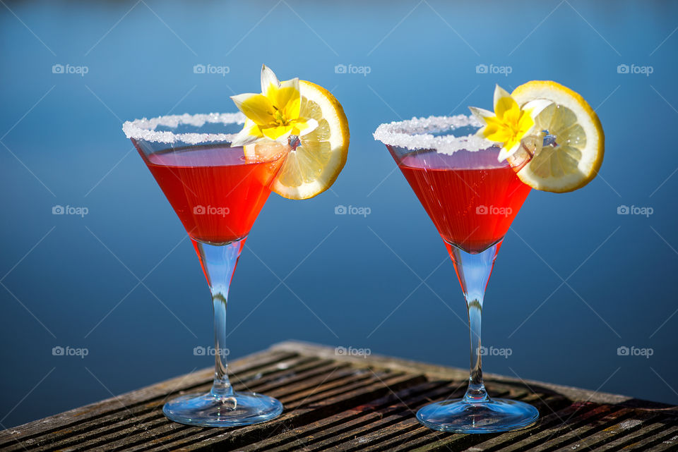 Two cocktail glasses on blue water background