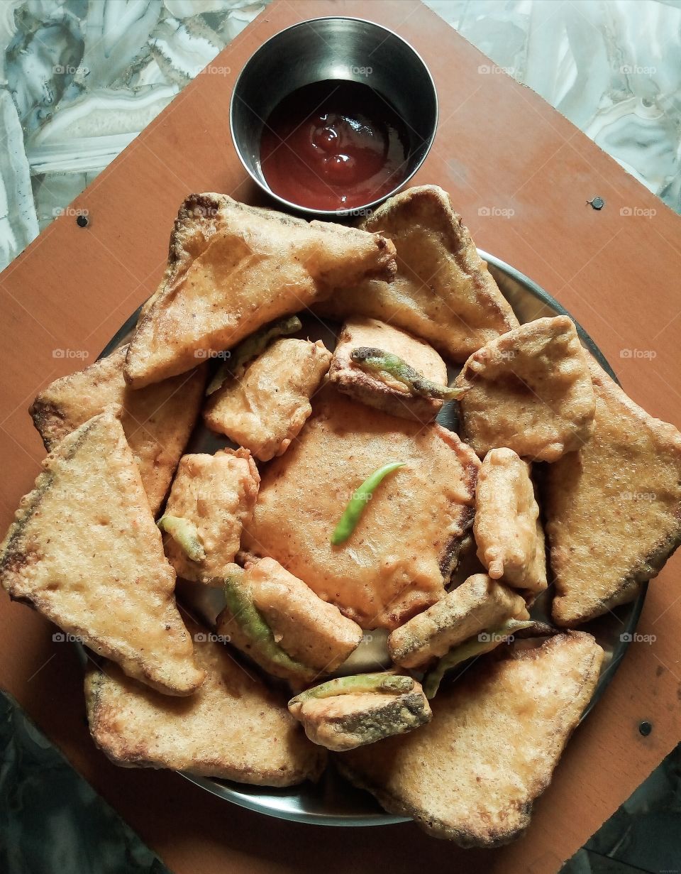 Bread Pakora is an Indian fried snack (pakora or fritter) served with sauce. A common street food, it is made from bread slices, gram flour, and spices among other ingredients.