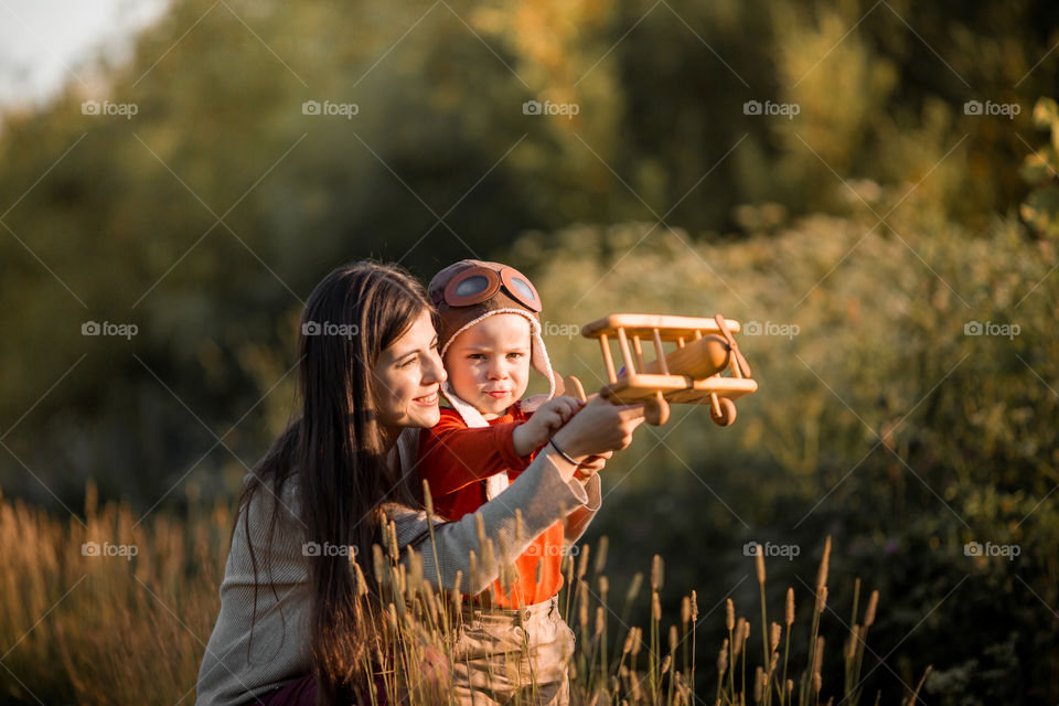 Mother and son with wooden plane at sunset