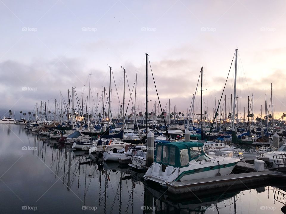 Long Beach harbor filled with several sizes of boats, still water, overcast, sunset