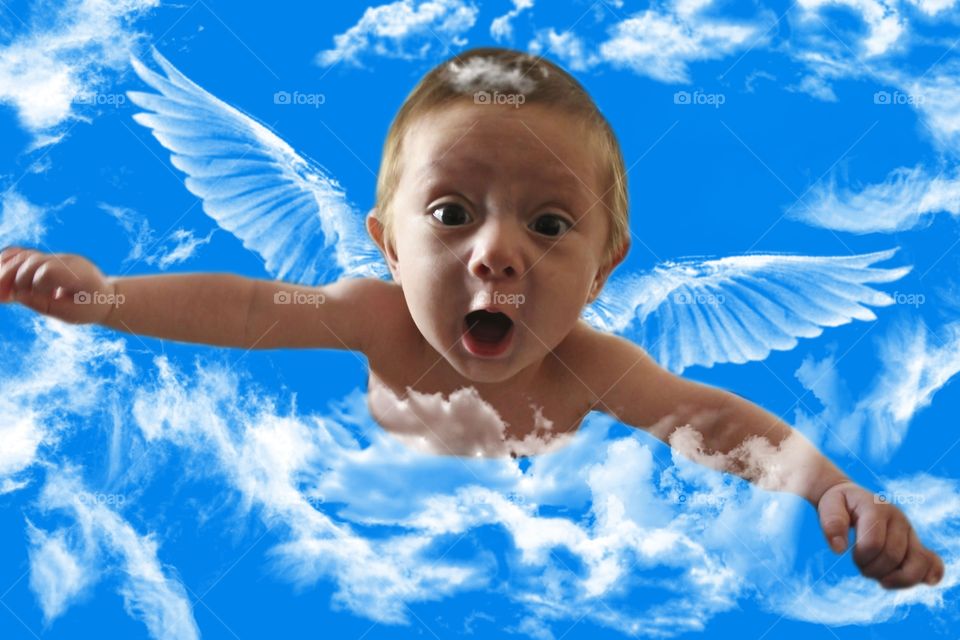 Little boy with fairy wings flying in sky