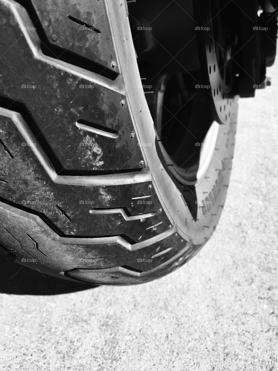 The tire of a motorcycle on a sunny day. 