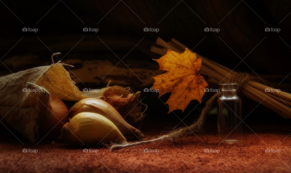 Maple leaf in a small bottle against autumn harvest background.
