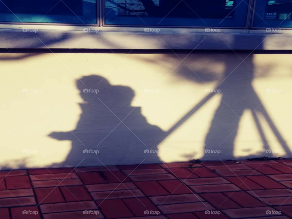 an shadow of a child who's  walking around at the back of her mother.
