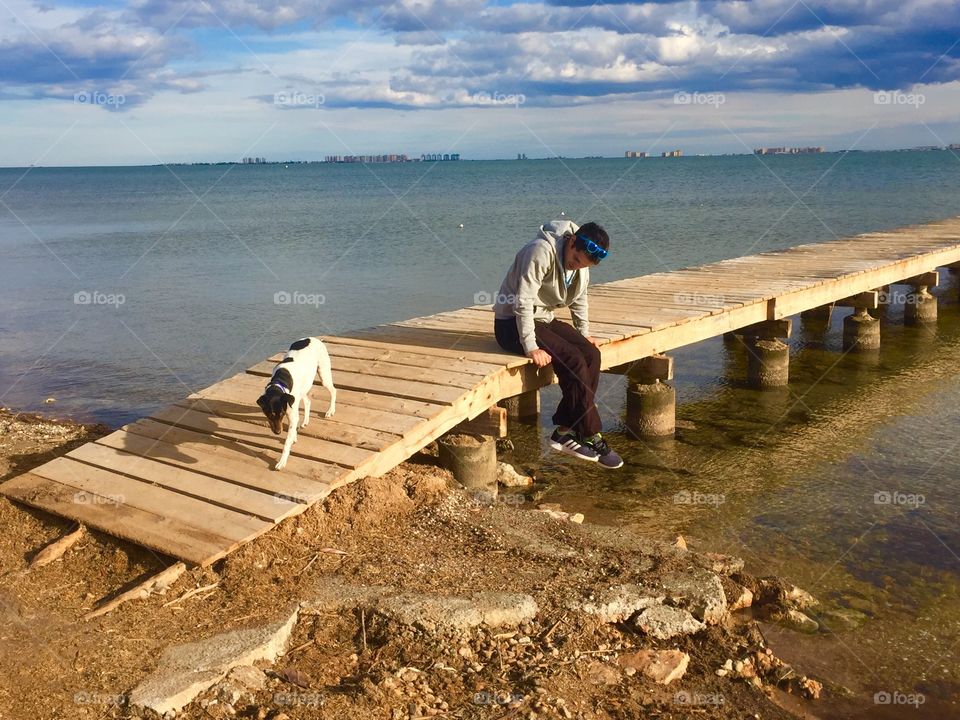 Image of a man sitting on a pier, deep in thought, with his dog walking onto the beach. In the background is the mar menor strip, a man made strip of land with properties built on it - these properties appear to float in the sea.
Location - Murcia, Spain