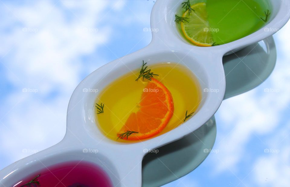 Fruit jelly decotated with lemon, orange and herbs on a background with the reflection of the sky